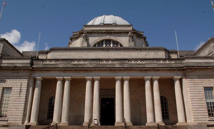 view of the outside of museum building. It looks grand, has steps leading up to the front and there are big stone pillars decorating the frontage.